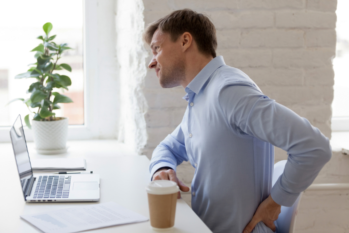 Office worker having strong lower back pain bad posture