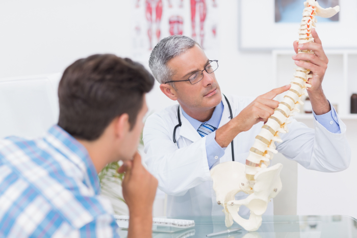Doctor explaining anatomical spine to his patient in medical office