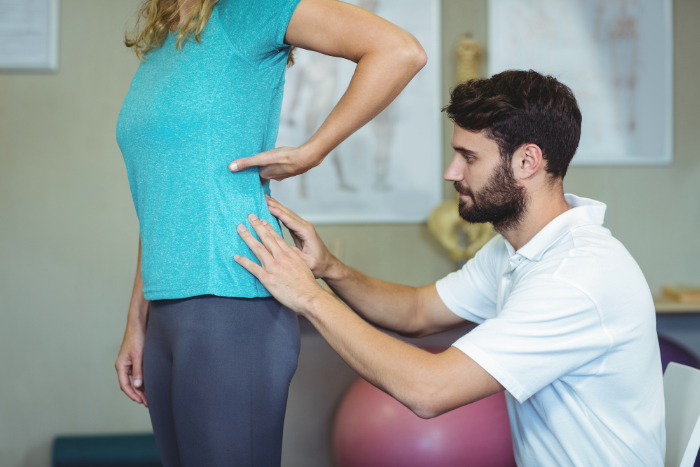 physiotherapist examines womens lower back