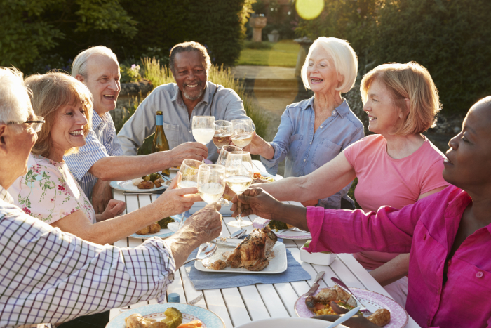 Group Of Senior Friends Making A Toast At Outdoor Dinner Party