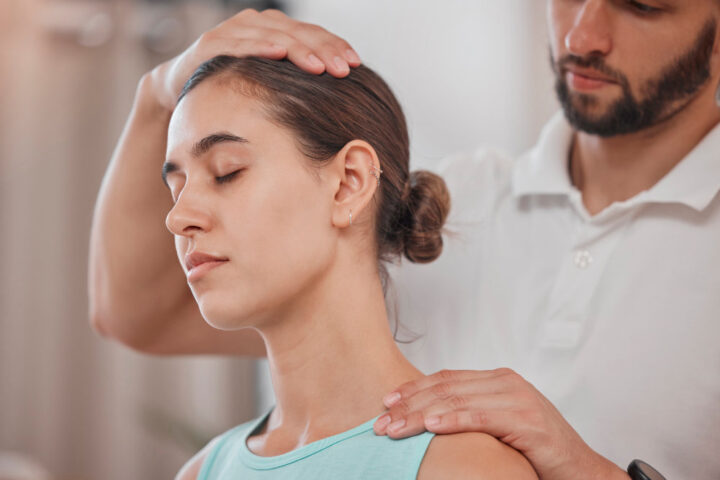 physiotherapist stretching woman neck pain in clinic